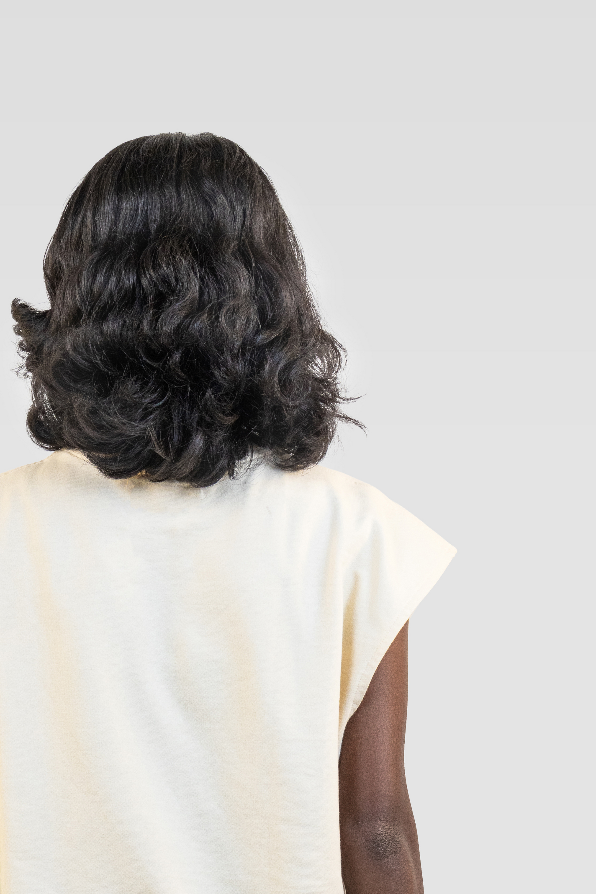 Back view of a model wearing the Harper Slein Foundation Tank in OG Off White on a white background.