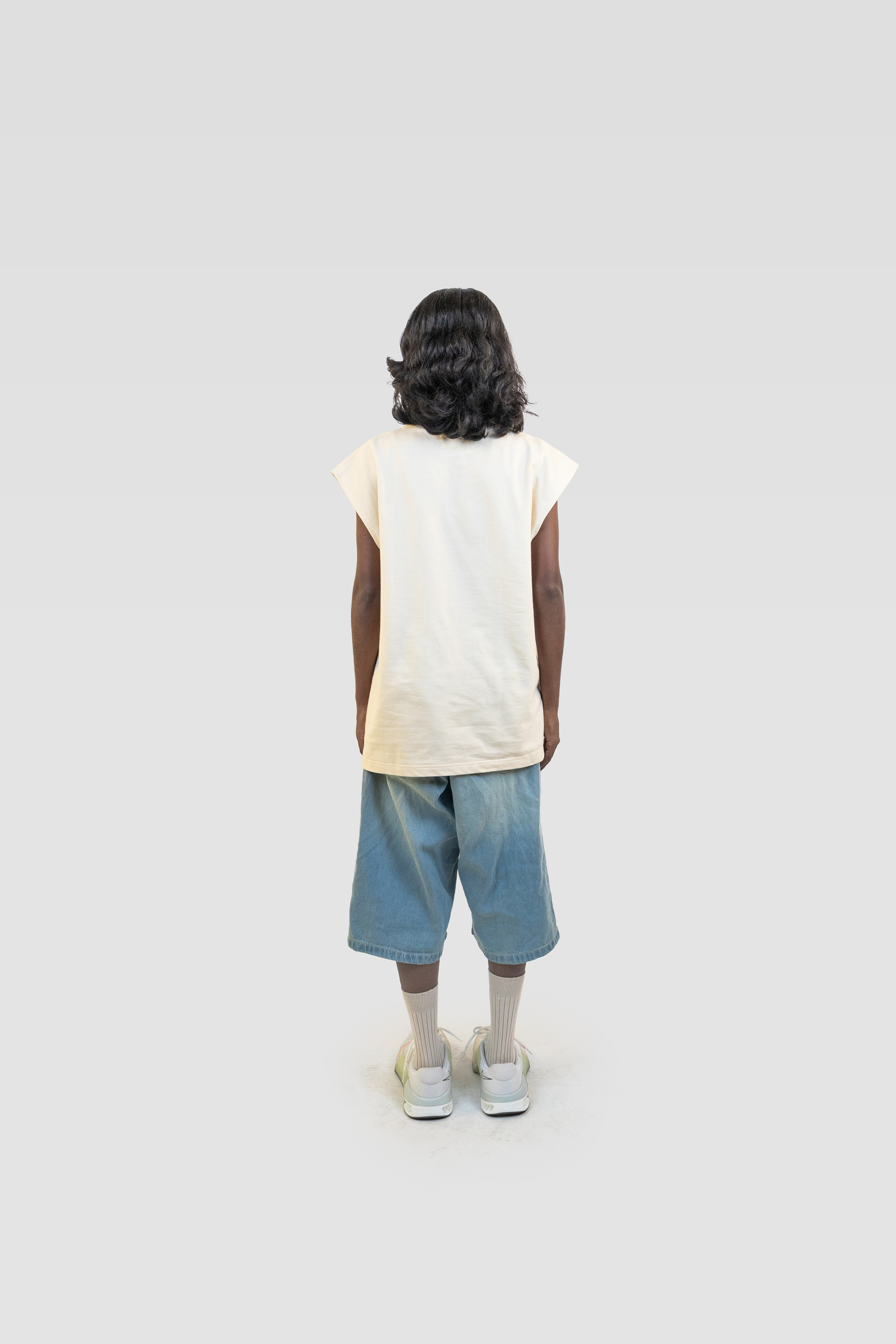 Full body back view of model wearing the Harper Slein Foundation Tank in OG Off White, paired with denim shorts and sneakers.