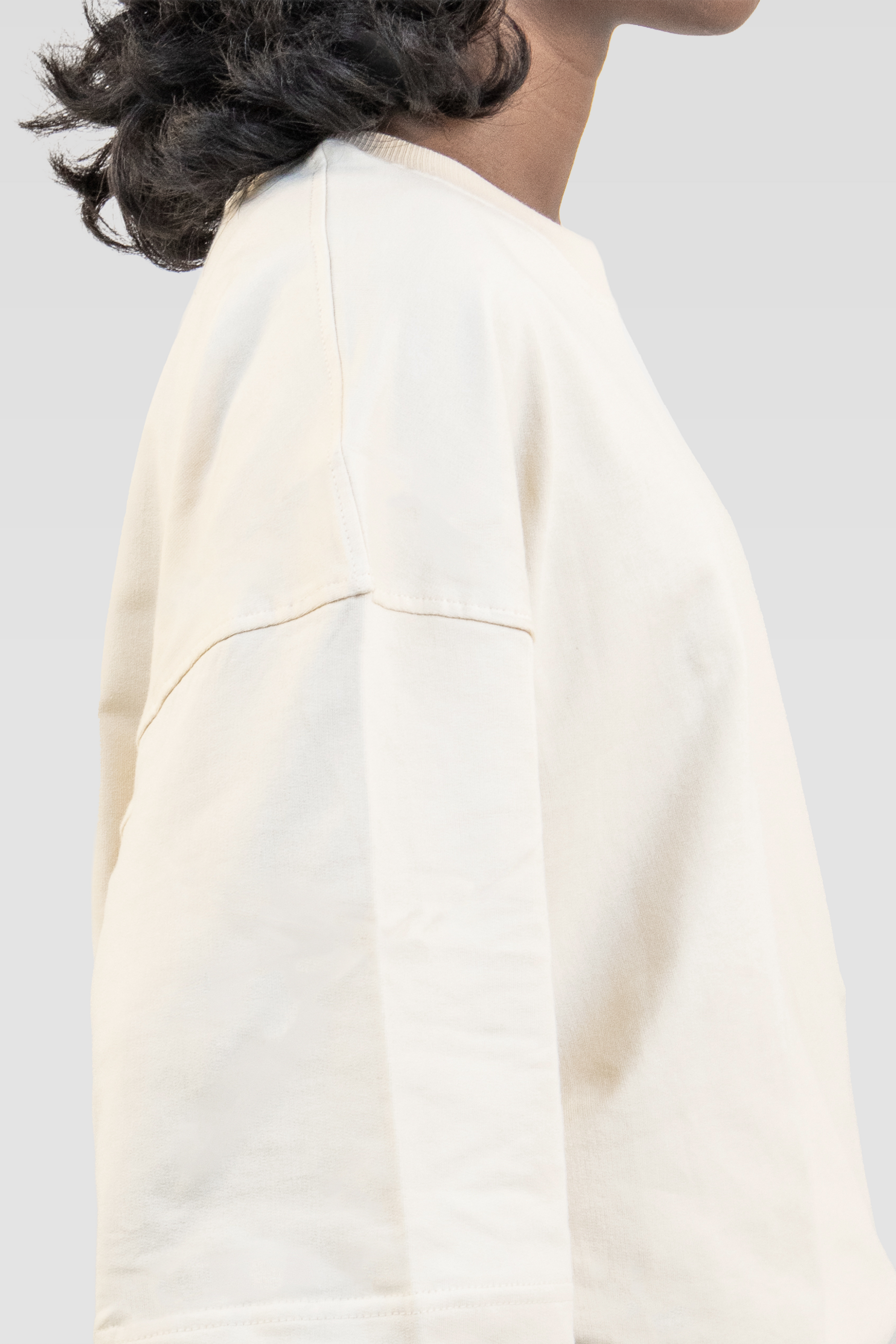 Close-up side view of a model wearing Harper Slein Off White oversized tee in premium 240 GSM cotton, showcasing its clean stitching, dropped shoulder, and soft drape against a plain background.