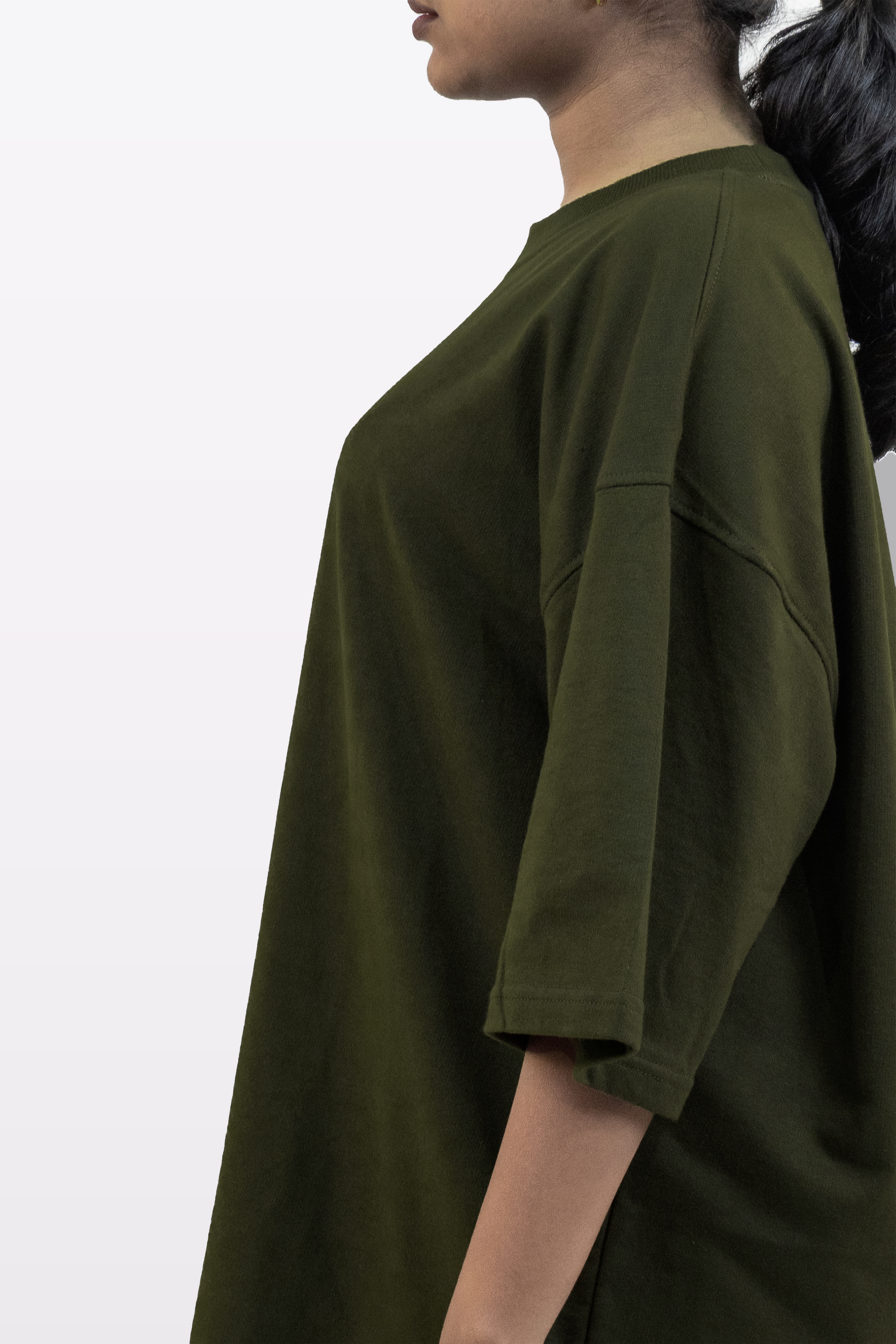 Side profile of a female model wearing the Harper Slein oversized t-shirt in Nori Seaweed Green, showcasing its relaxed fit, dropped shoulders, and premium 240 GSM cotton fabric.