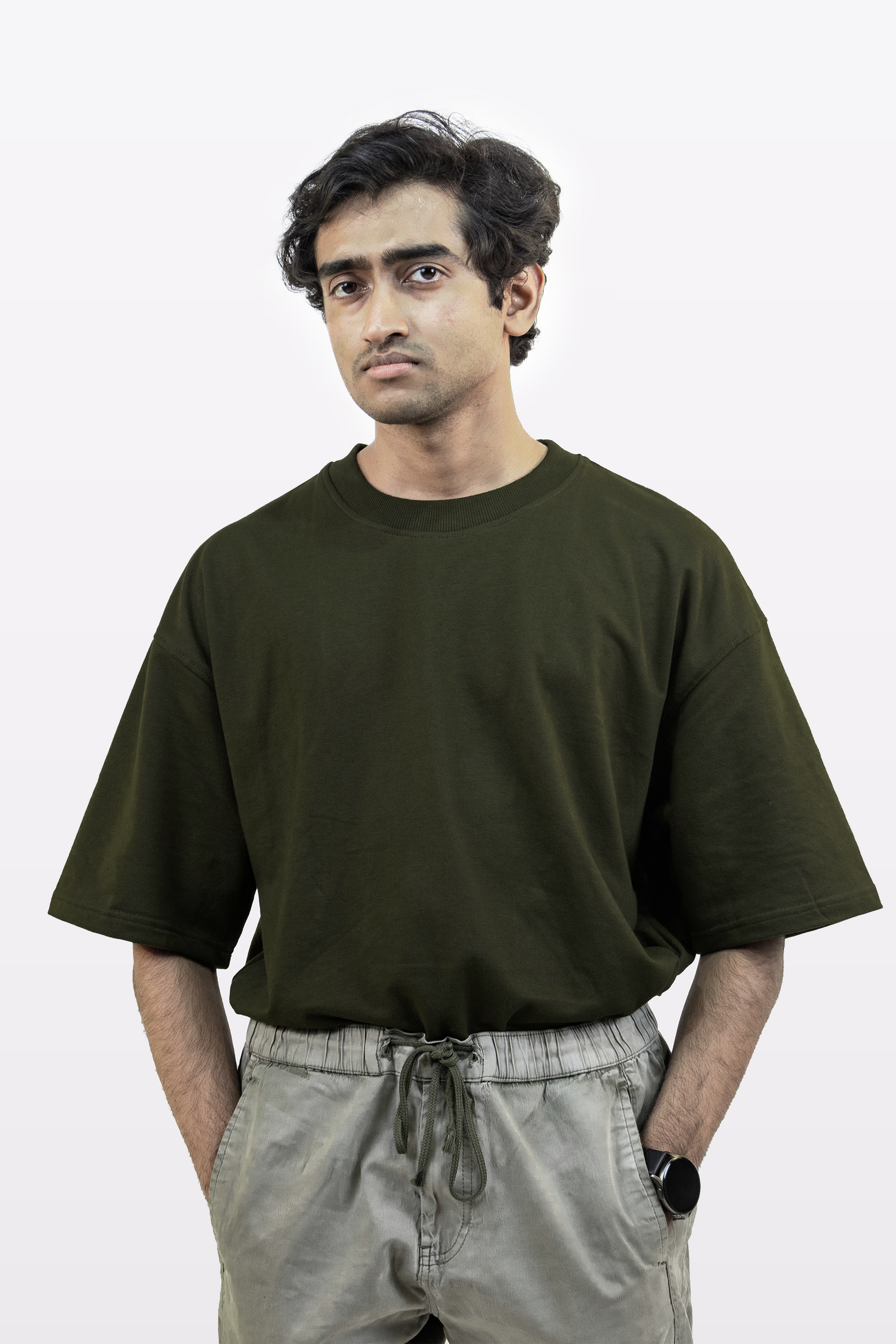 Male model wearing the Harper Slein oversized t-shirt in Nori Seaweed Green, paired with light gray drawstring pants, standing against a white background.