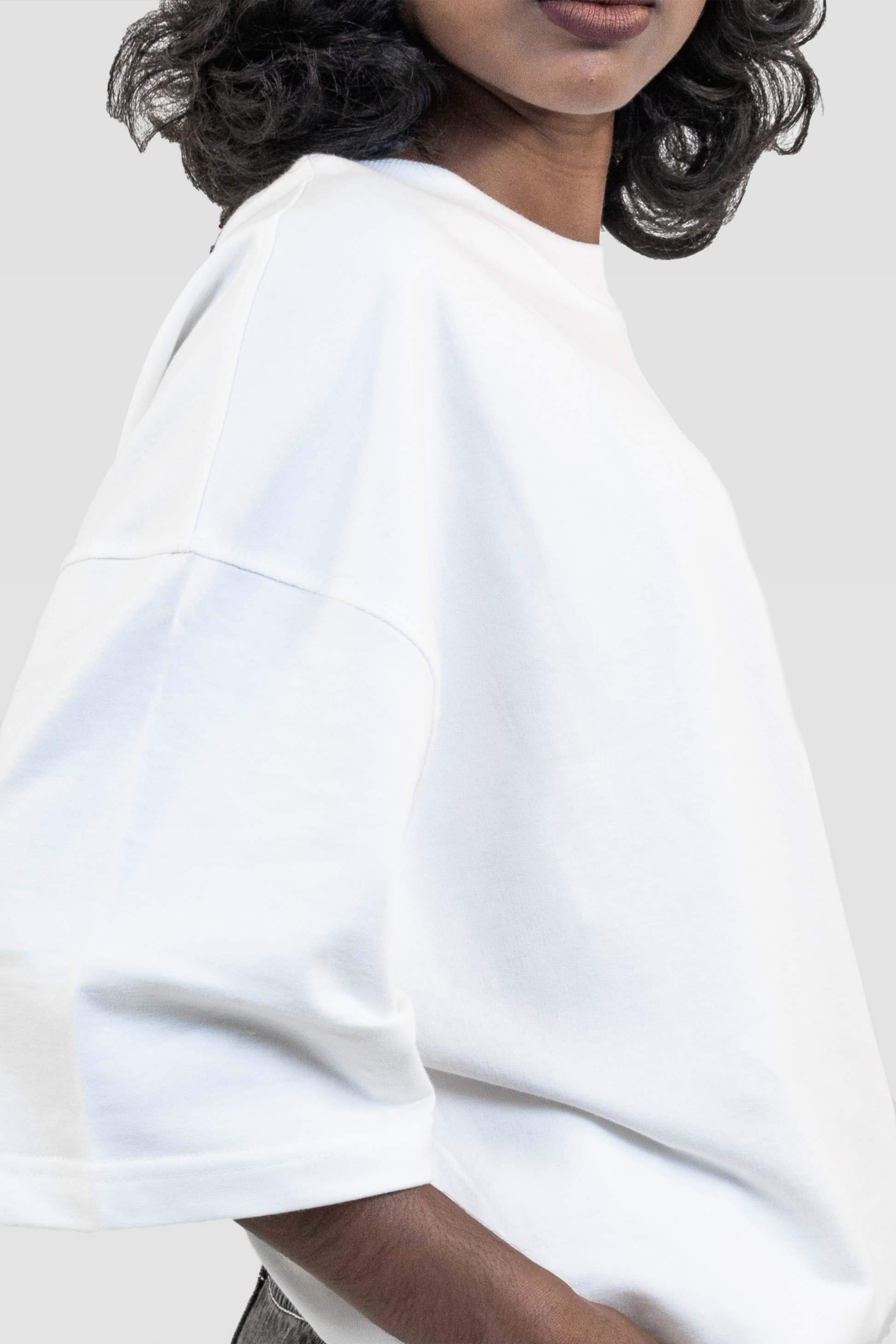 Close-up of a female model wearing Harper Slein oversized t-shirt in Blank White against a light gray background