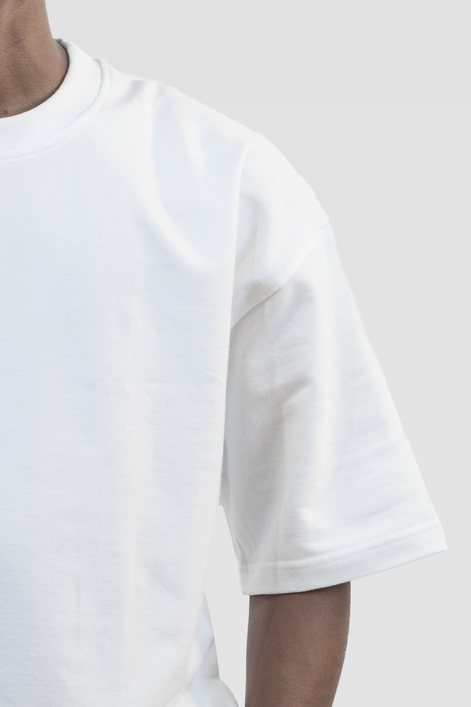 Close-up front view of a model wearing Harper Slein oversized t-shirt in Blank White against a light gray background