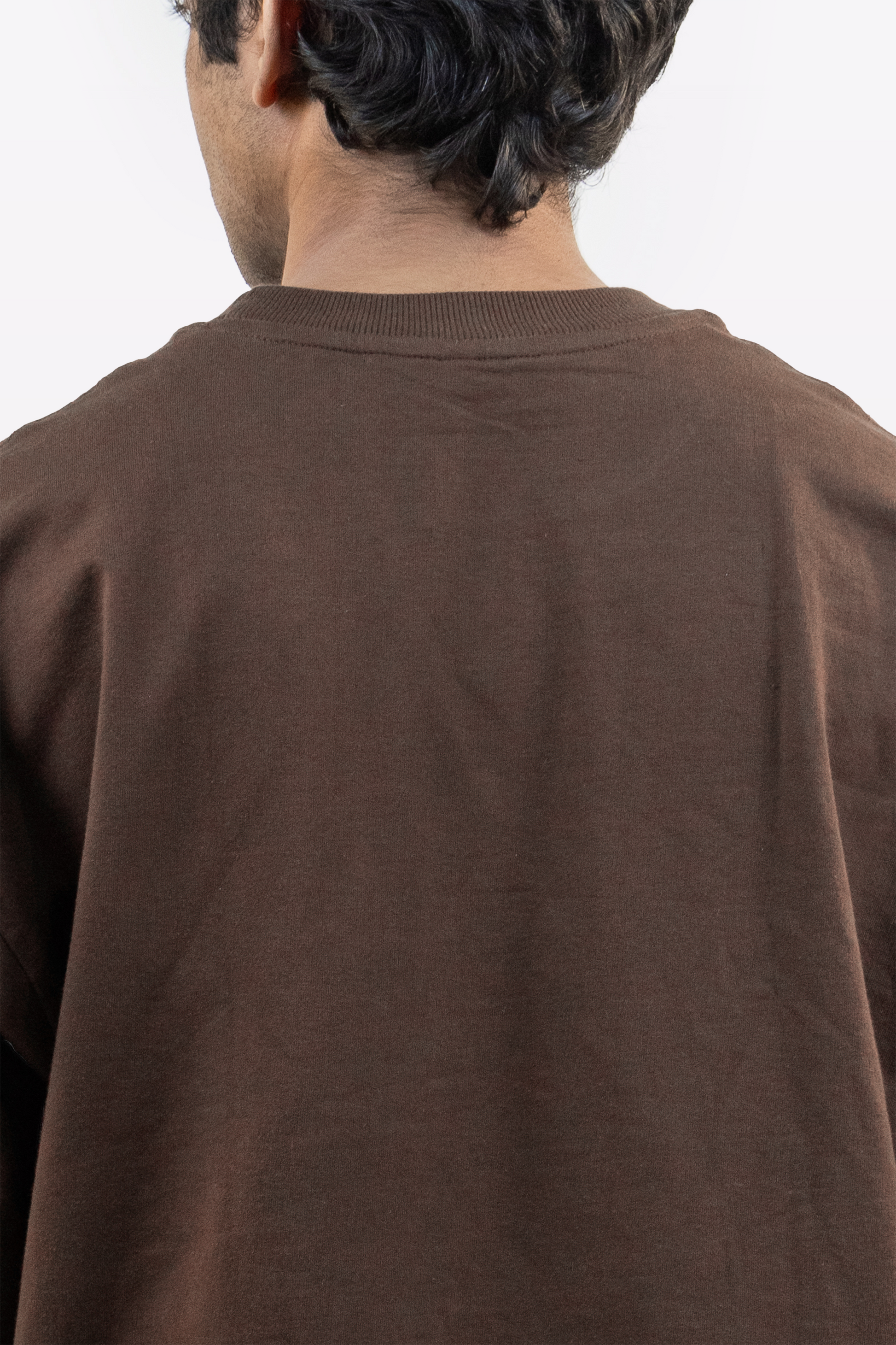Close-up back view of a model wearing Harper Slein oversized t-shirt in Cacao on a white background
\