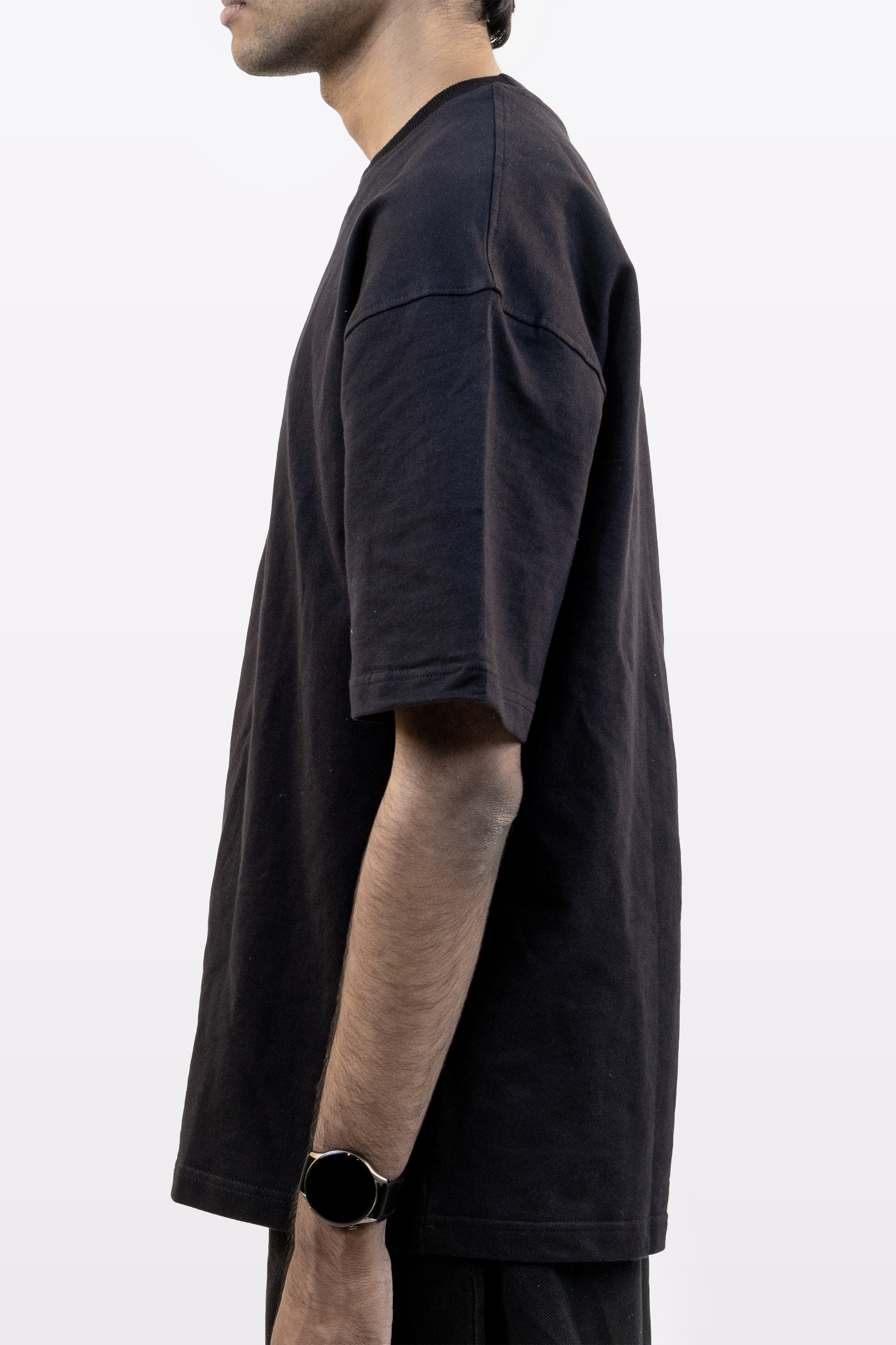 Close-up side profile of male model wearing Harper Slein oversized t-shirt in Classic Black on a white background