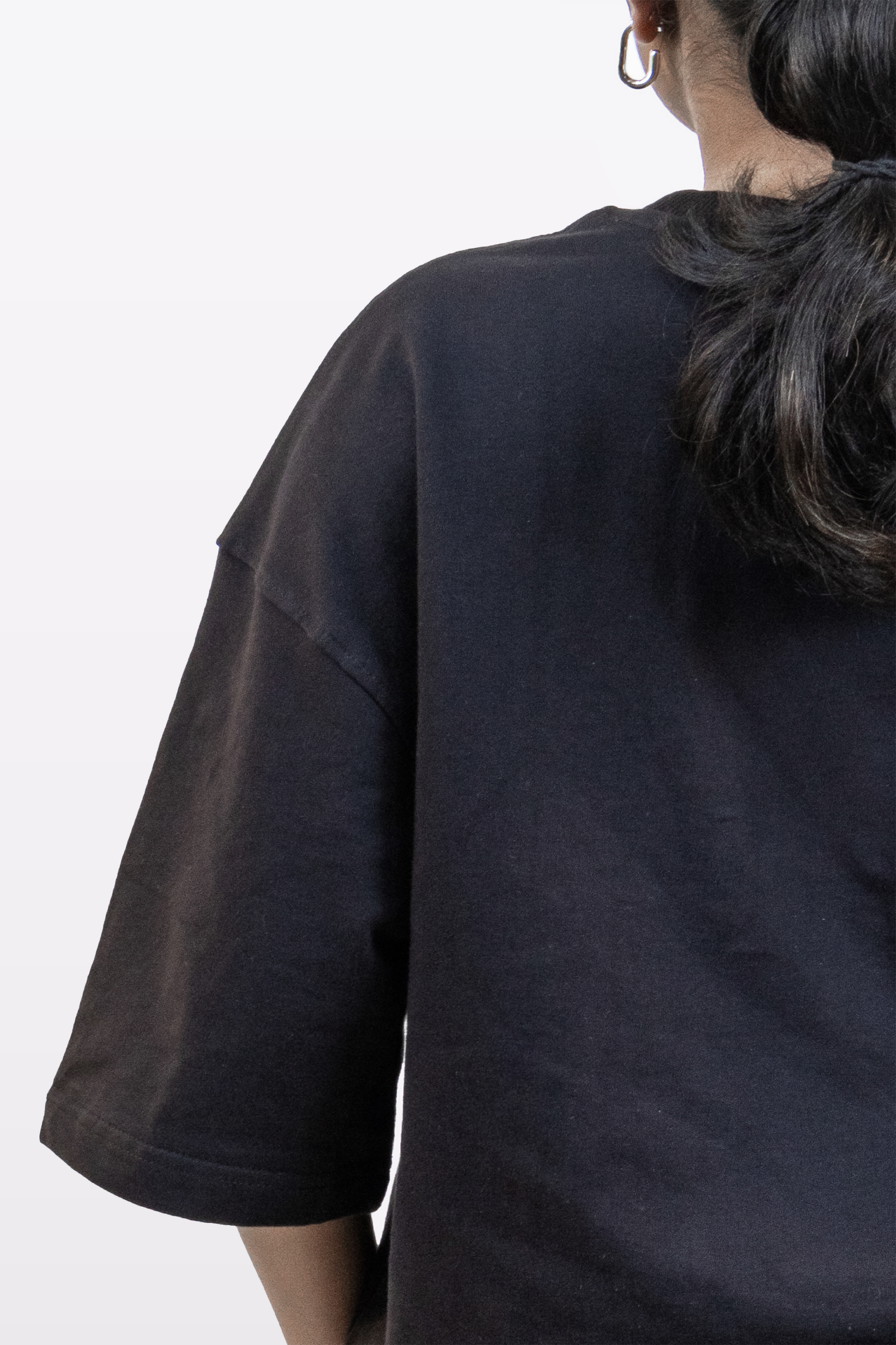 Close-up of female model showing back shoulder detail of Harper Slein oversized t-shirt in Classic Black on a white background