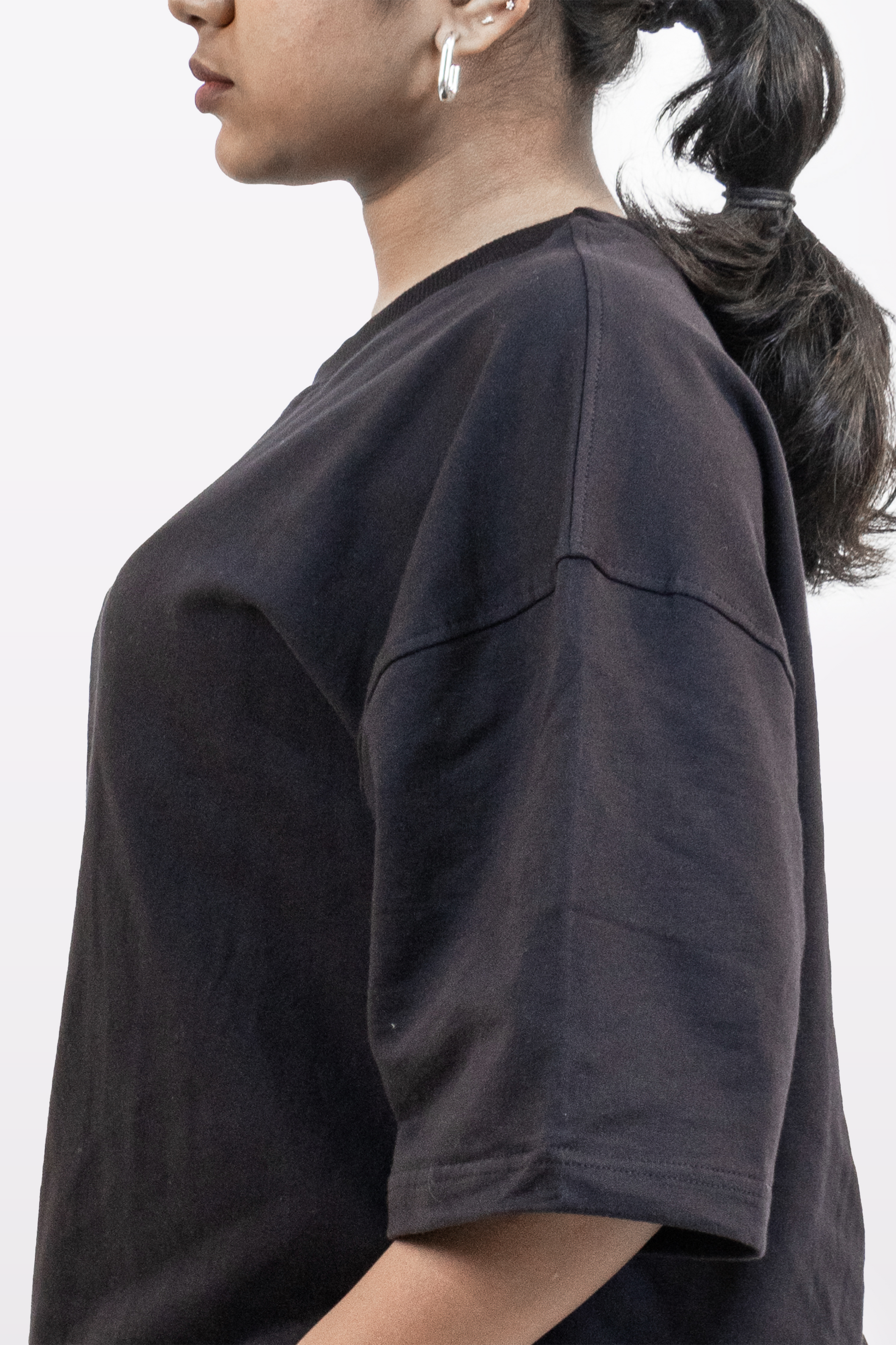 Close-up side view of female model showing sleeve and shoulder seam detail of Harper Slein oversized t-shirt in Classic Black on a white background