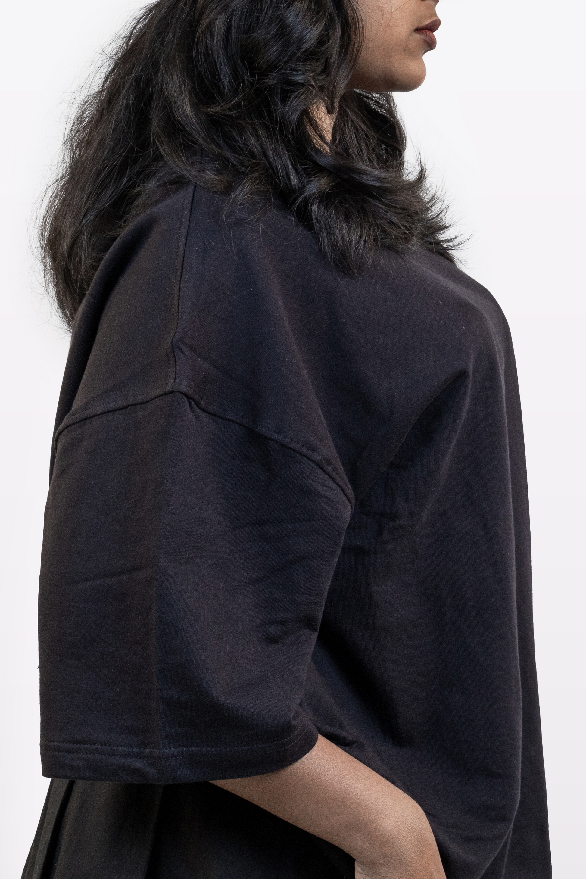 Close-up side view of female model wearing Harper Slein oversized t-shirt in Classic Black, highlighting shoulder seam, sleeve, and fabric texture against a white background