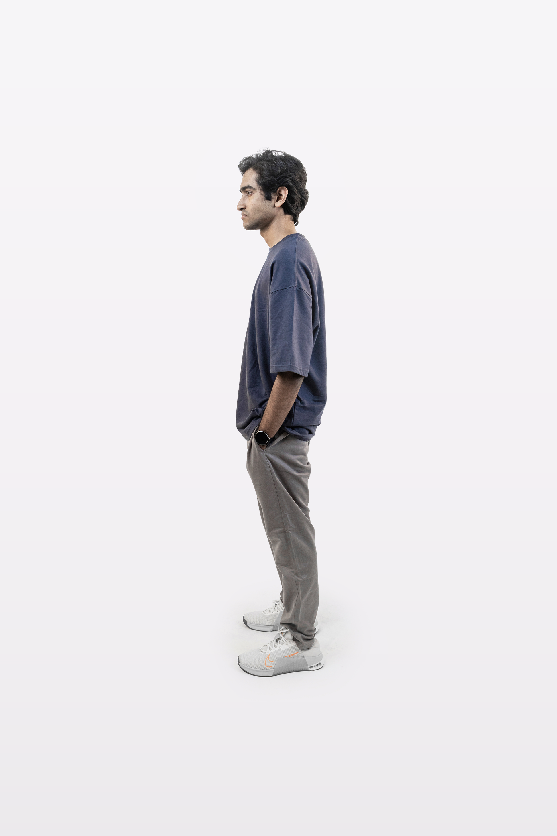Model wearing Harper Slein oversized t-shirt in Compass Blue with gray pants, side profile view, on a white background