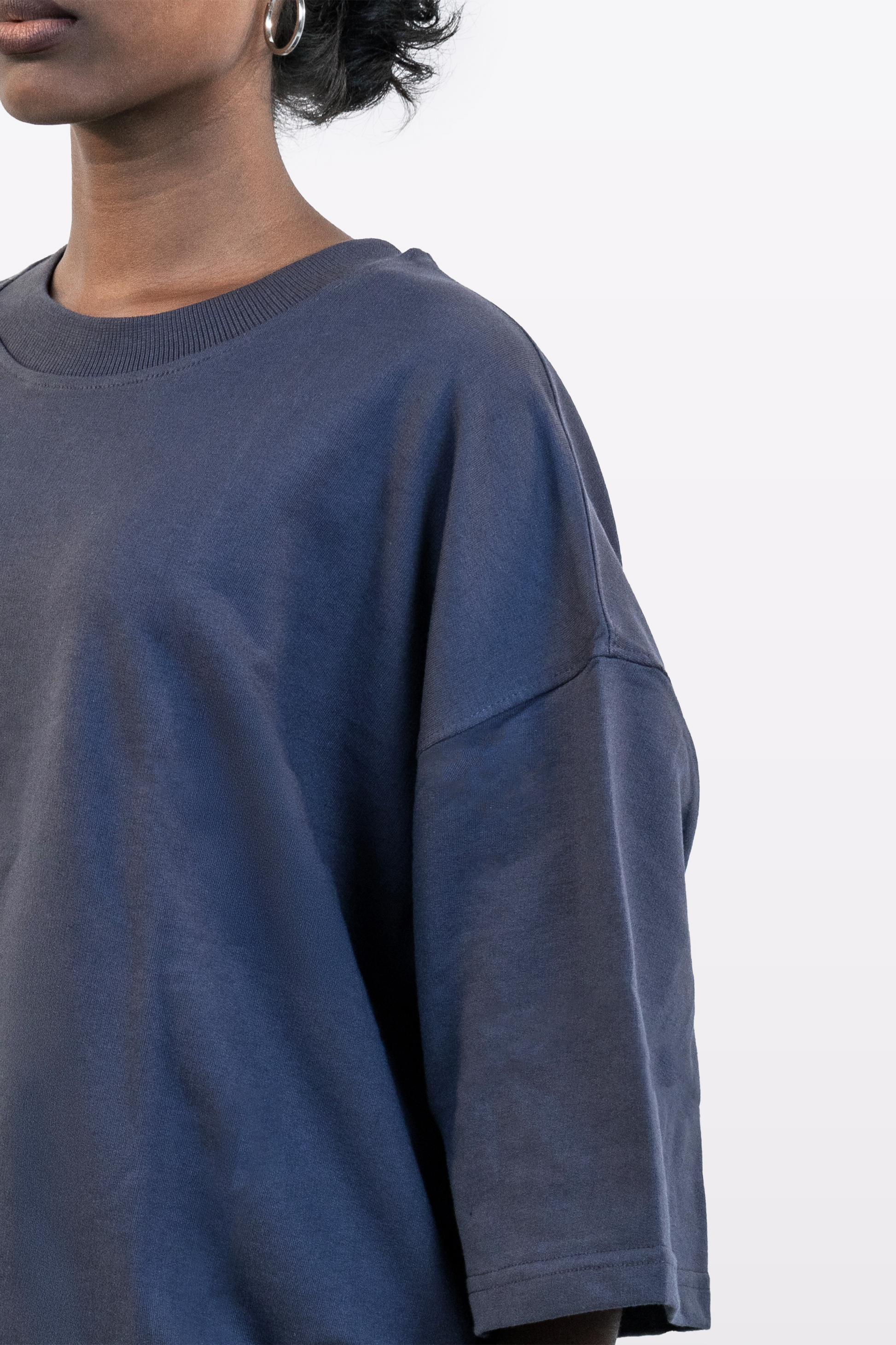 Close-up of model wearing Harper Slein oversized t-shirt in Compass Blue, highlighting collar and shoulder seam, on a white background