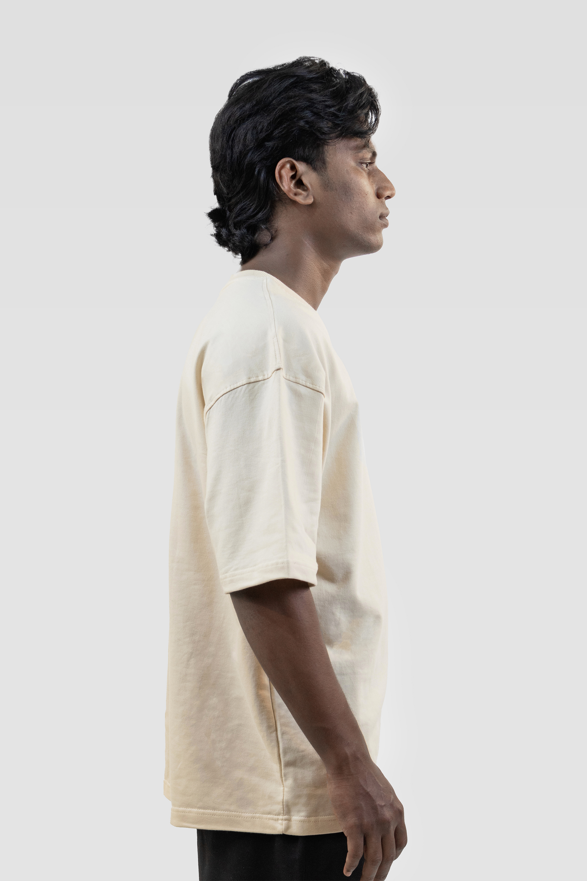 Side view of model wearing Harper Slein oversized t-shirt in OG Off White on a white background