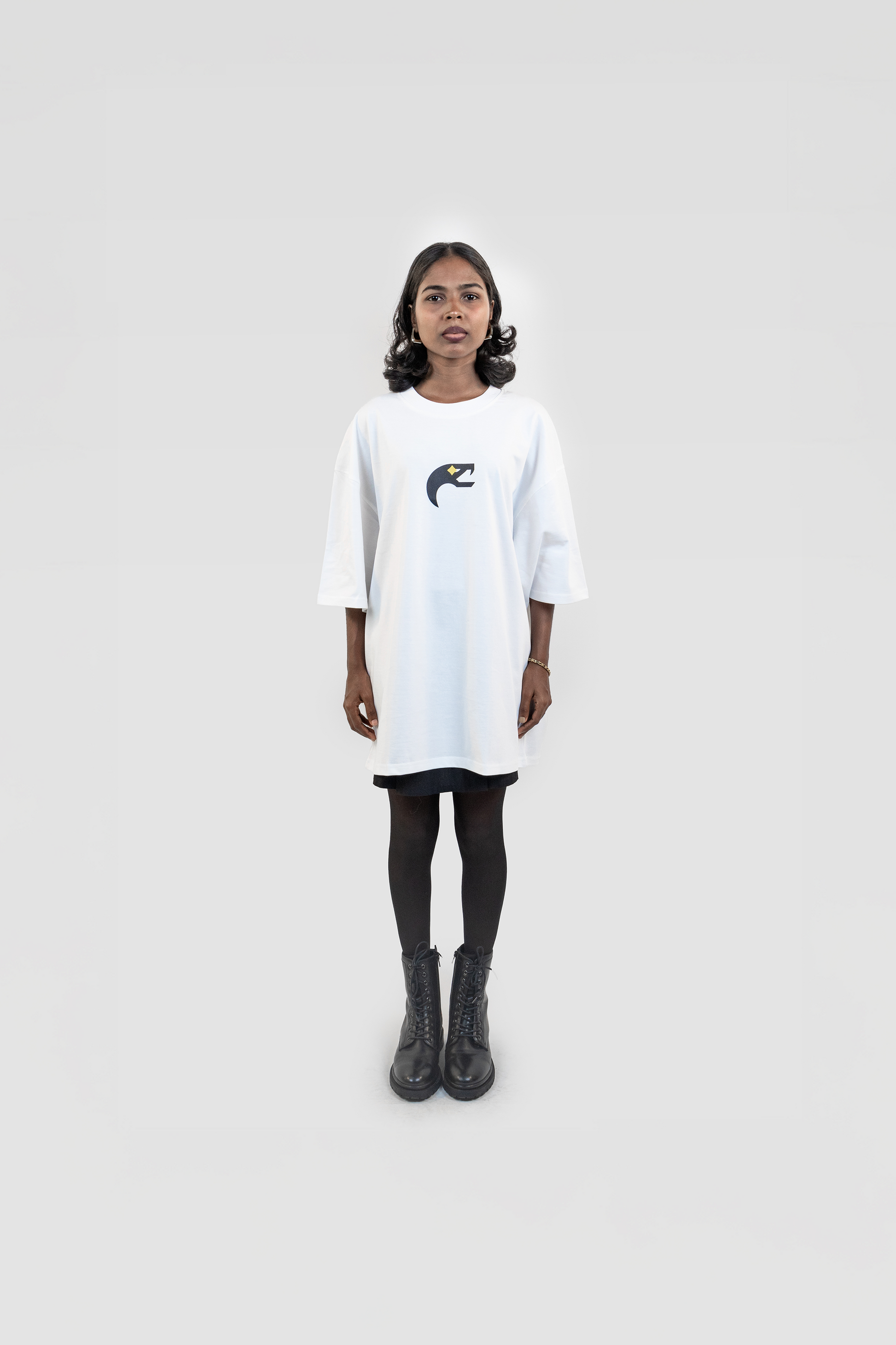 Front view of the Harper Slein Urban Crew Collection Snake Logo T-Shirt in white, featuring a black and yellow snake emblem on the chest, worn as an oversized fit with black tights and combat boots against a white background.