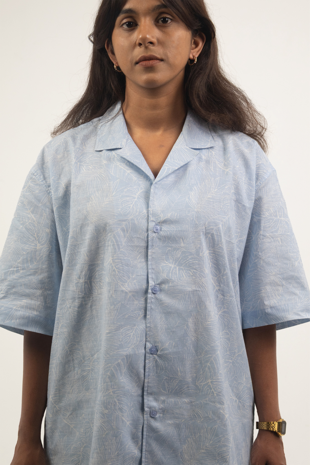 Woman wearing the Harper Slein Cuban Collar Sky Blue Shirt with subtle leaf patterns on a plain background