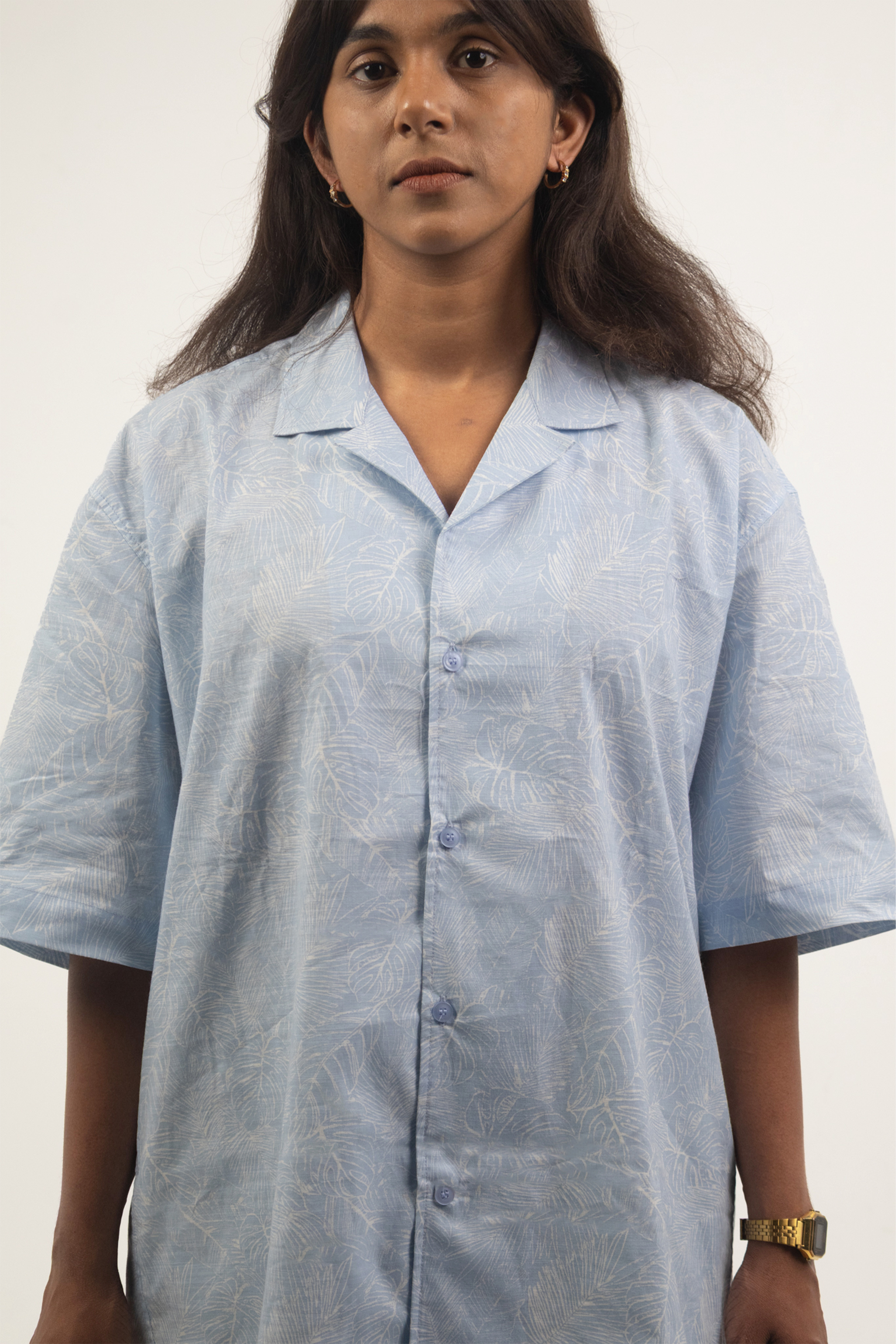 Woman wearing the Harper Slein Cuban Collar Sky Blue Shirt with subtle leaf patterns on a plain background