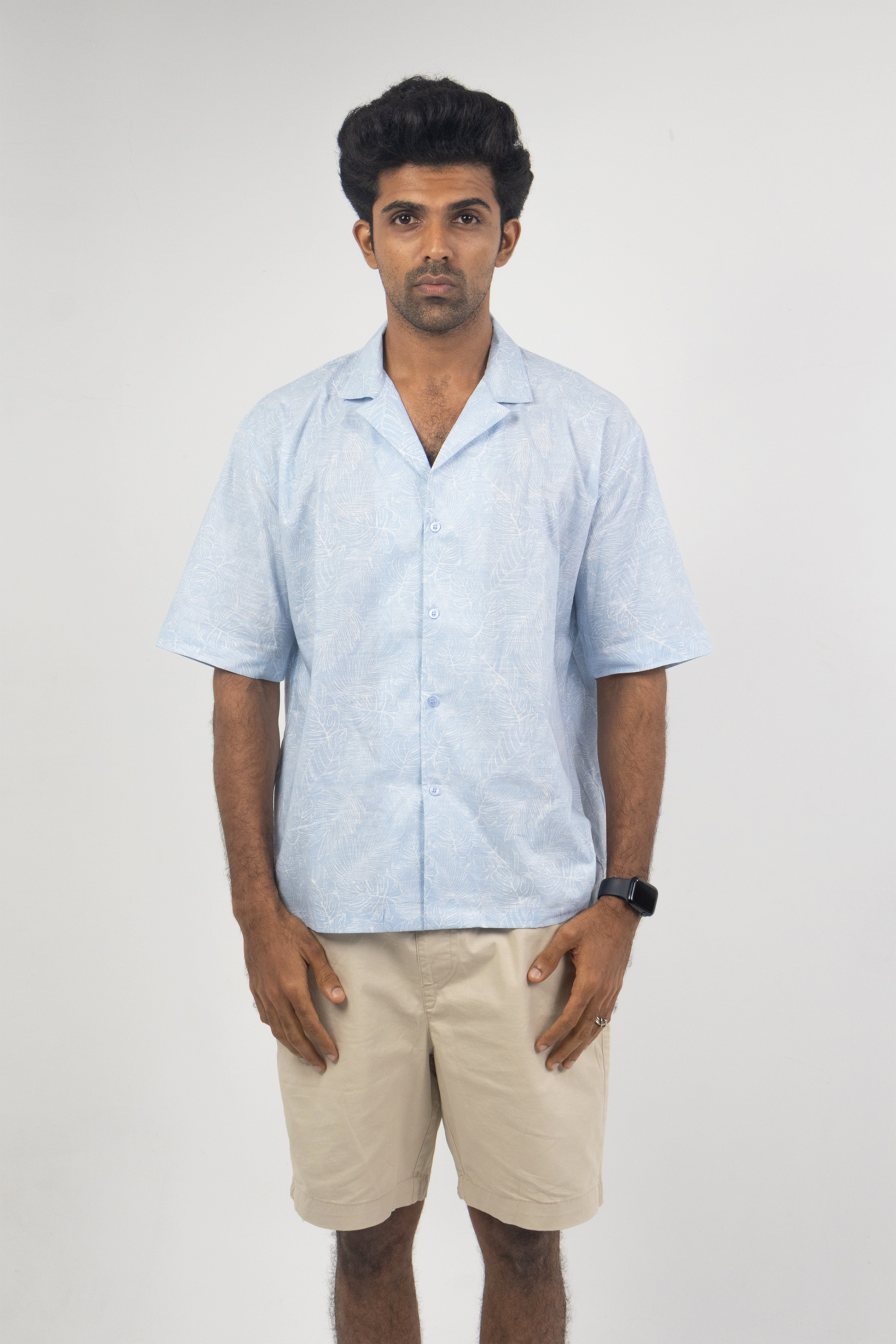 Man wearing the Harper Slein Cuban Collar Sky Blue Shirt with beige shorts, front view against a white background