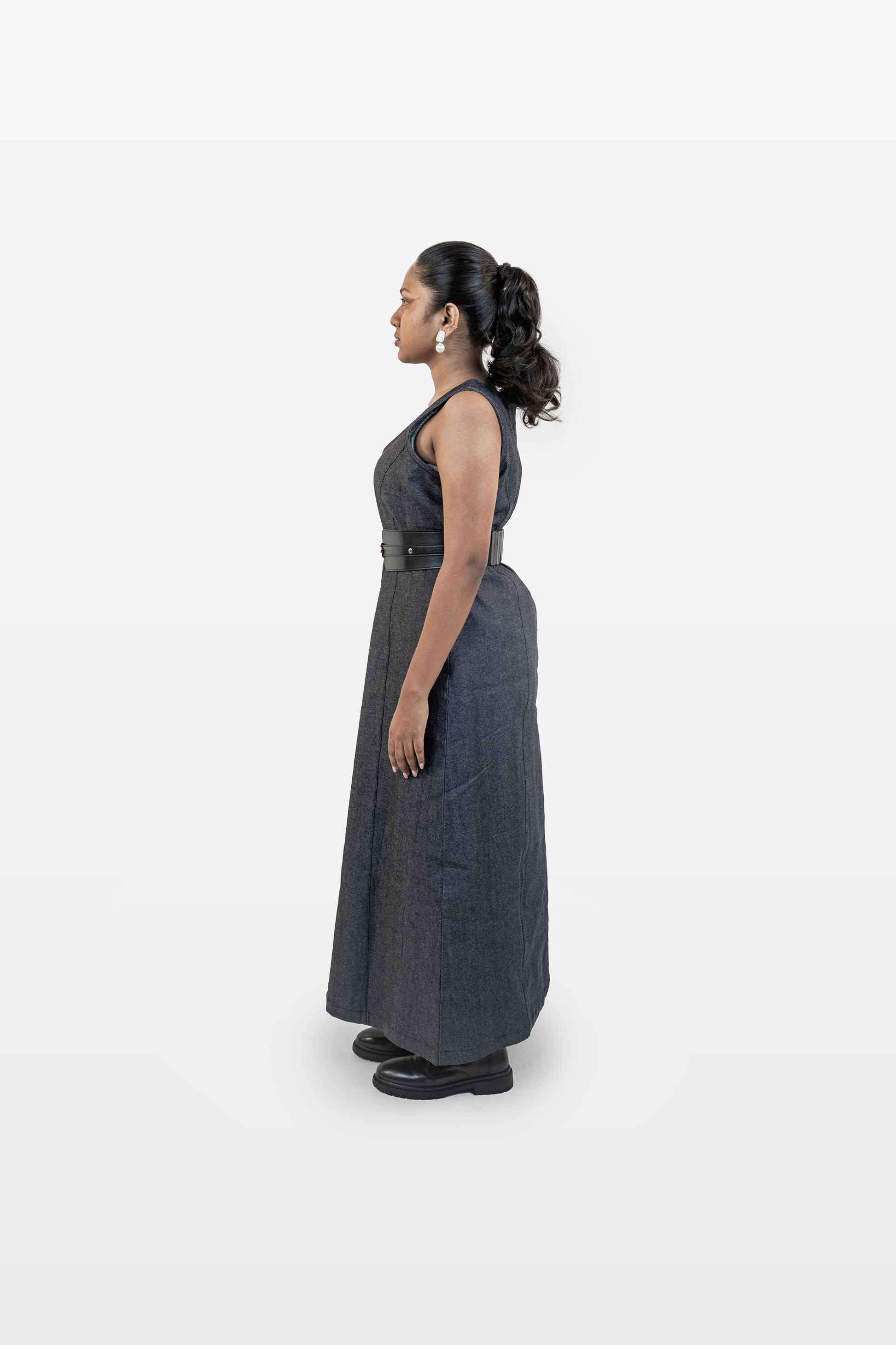 Model wearing Harper Slein sleeveless denim dress, side view, on a white background
