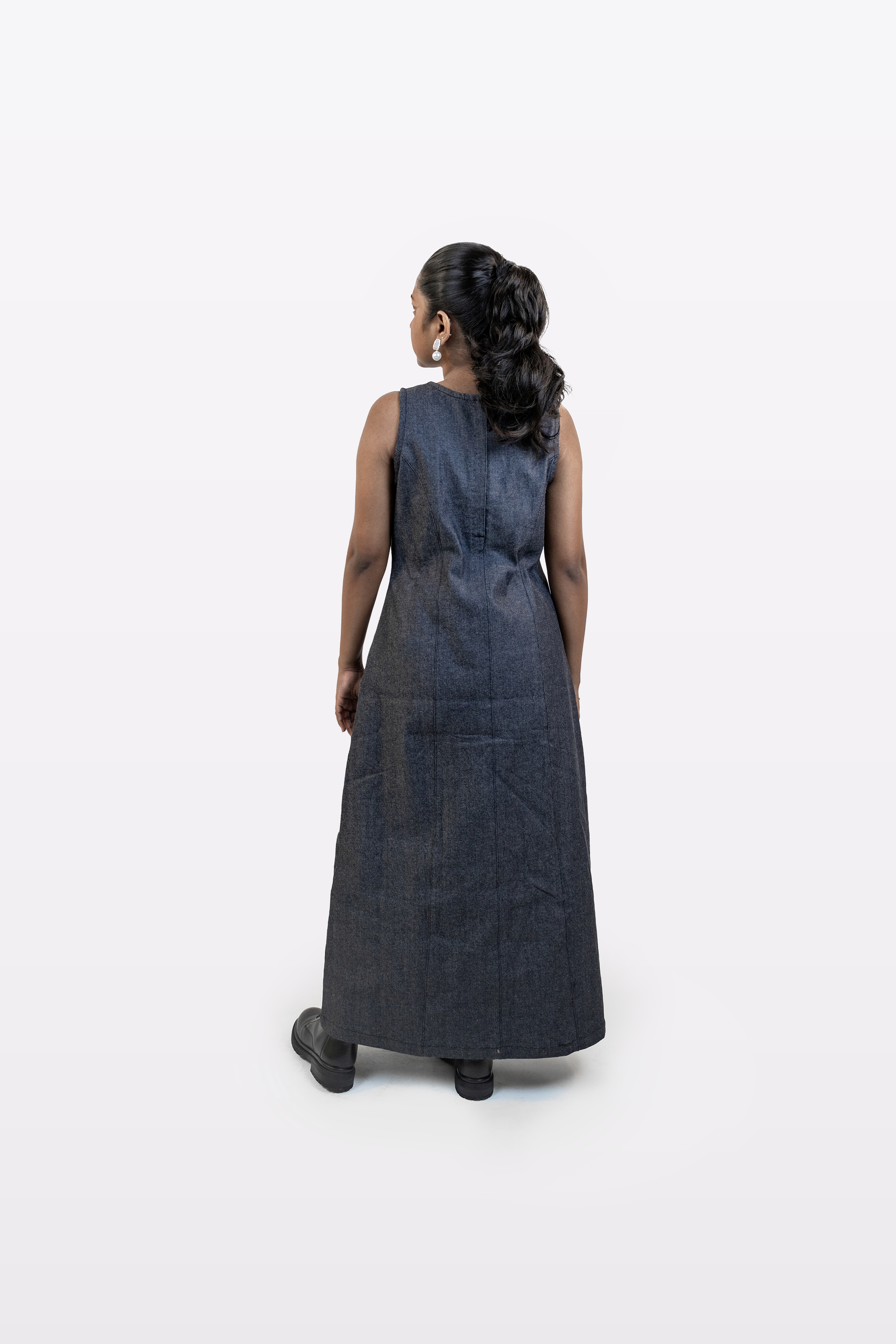 Back view of a model wearing the Harper Slein sleeveless denim dress, featuring a clean, structured silhouette, against a white background.