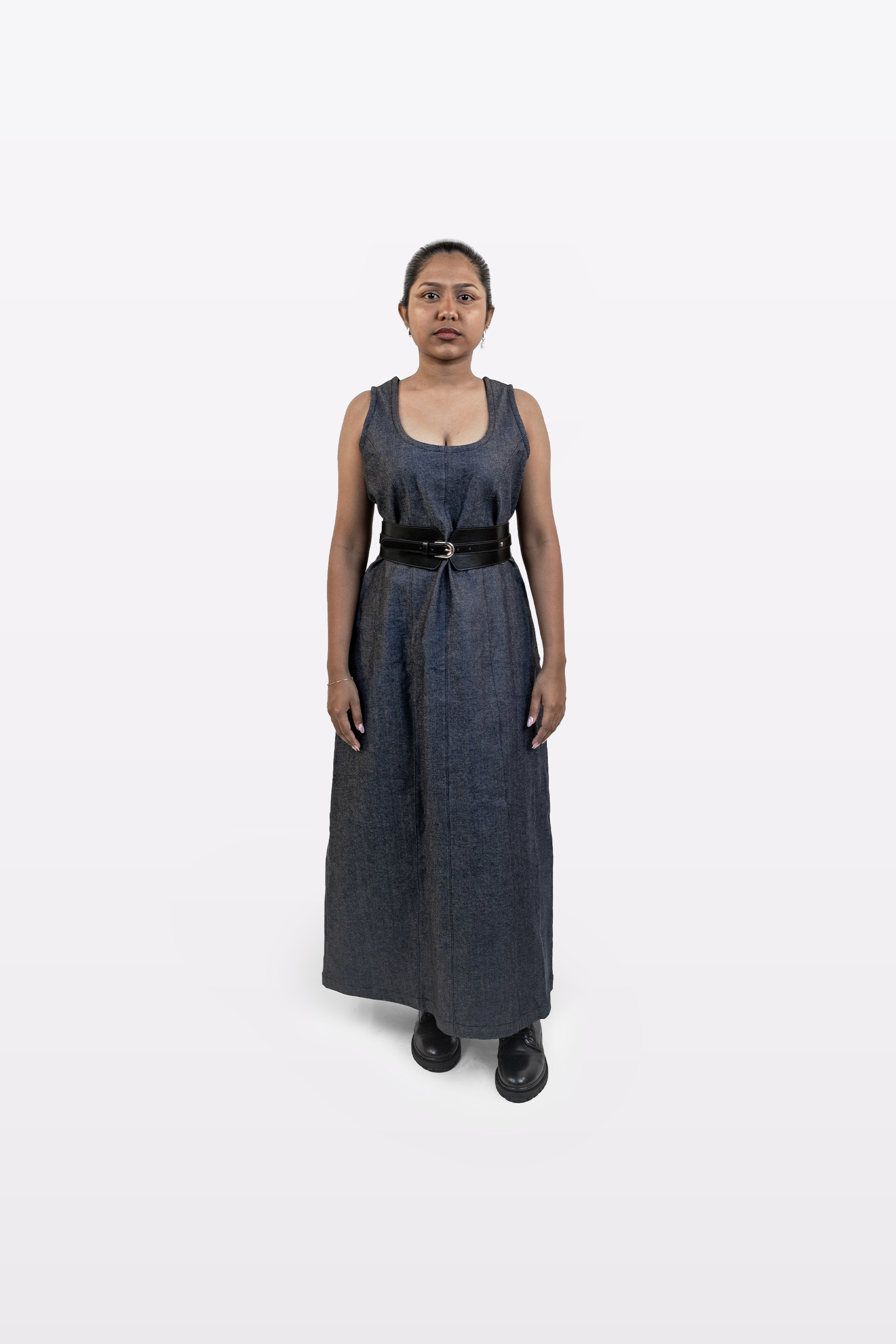 Model wearing Harper Slein sleeveless denim dress styled with a black belt, front view, on a white background
