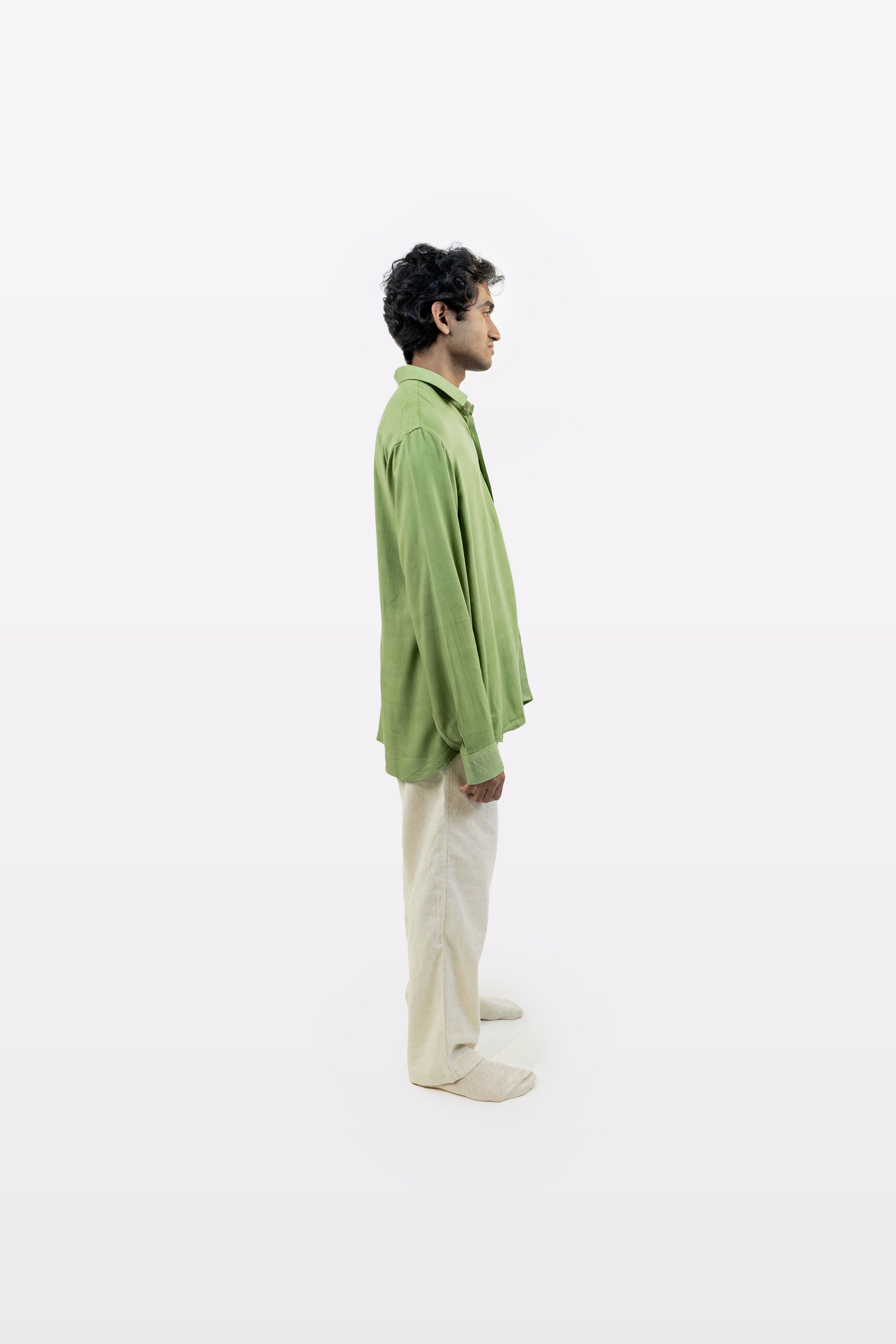 Full-body side profile of a model wearing the Harper Slein Moss Shirt in green, styled with beige pants, against a white background