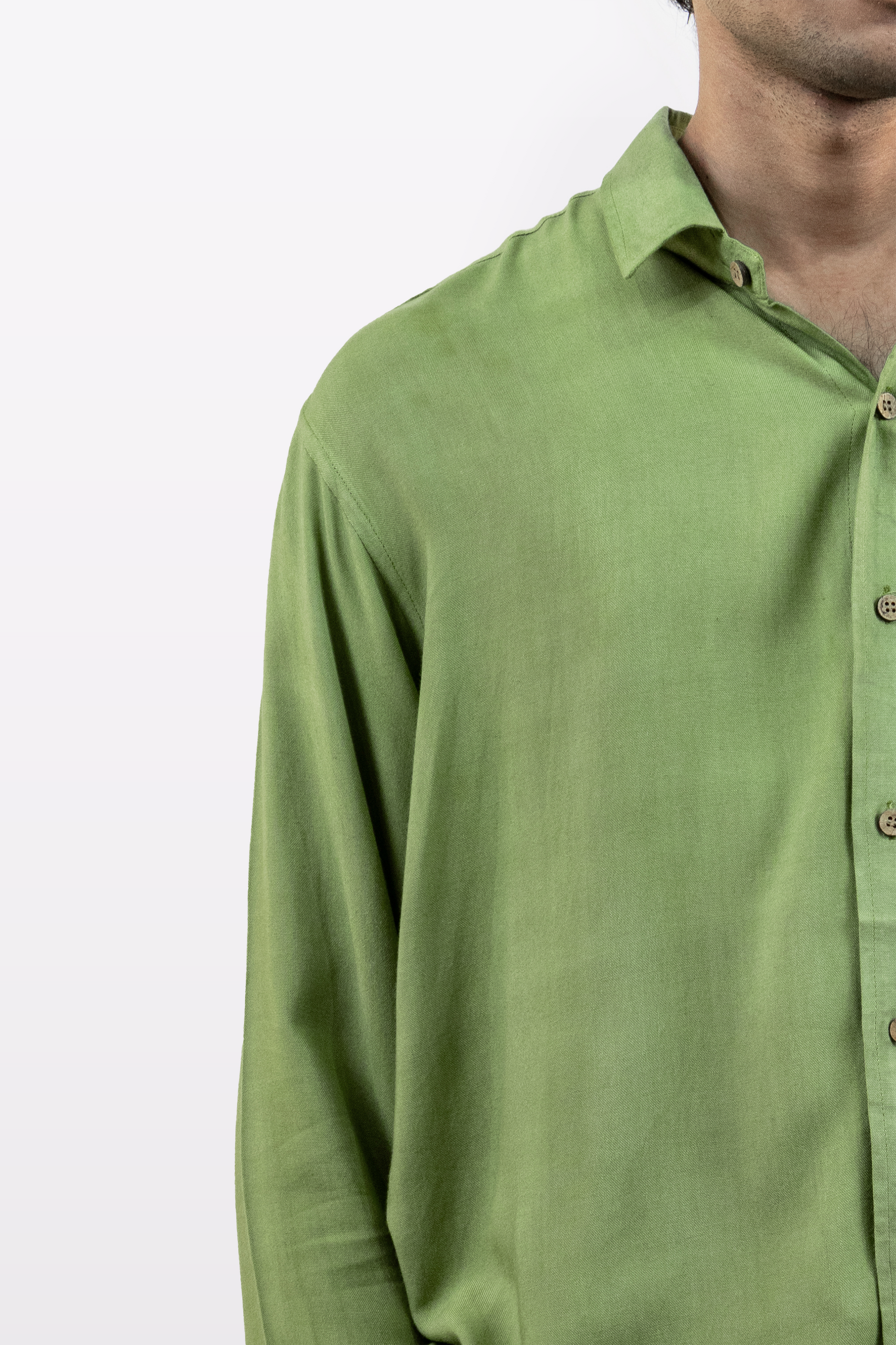 Close-up of a model wearing the Harper Slein Moss Shirt in green, showcasing fabric texture and button detail against a white background