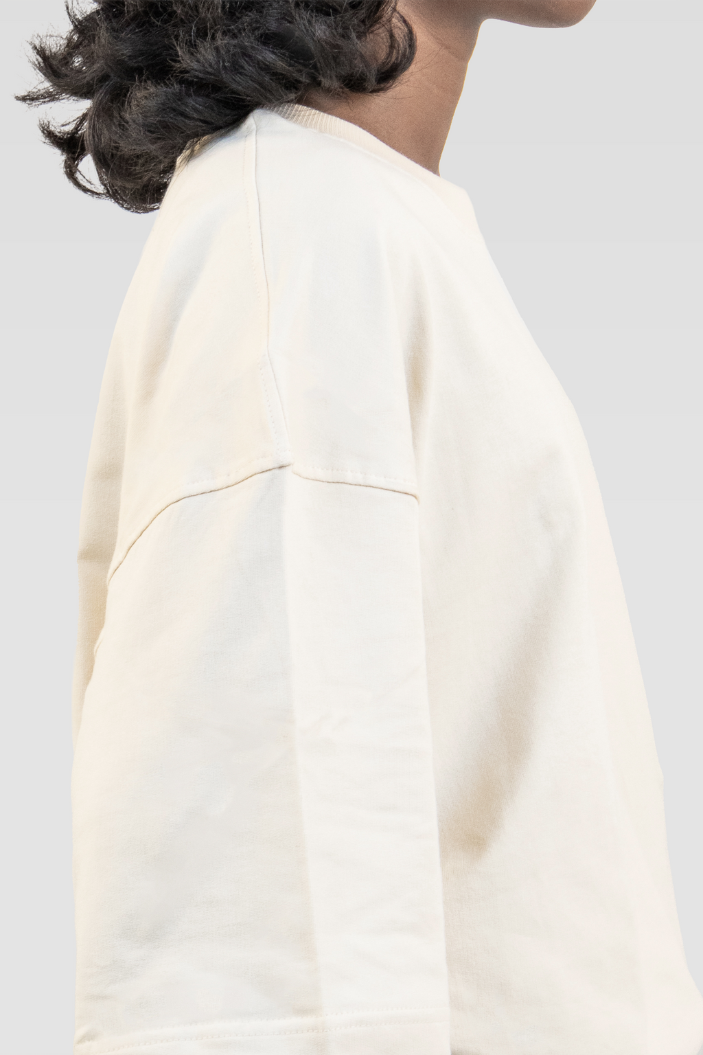 Close-up side view of a model wearing Harper Slein Off White oversized tee in premium 240 GSM cotton, showcasing its clean stitching, dropped shoulder, and soft drape against a plain background.