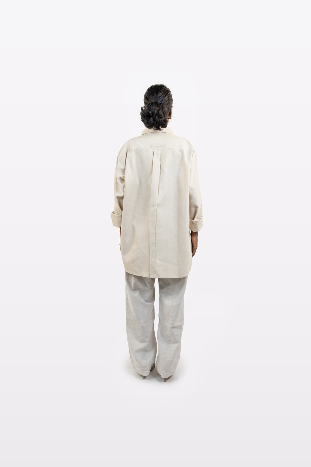 Full back profile of a model wearing the Harper Slein Off White Oxford Shirt with light trousers on a white background