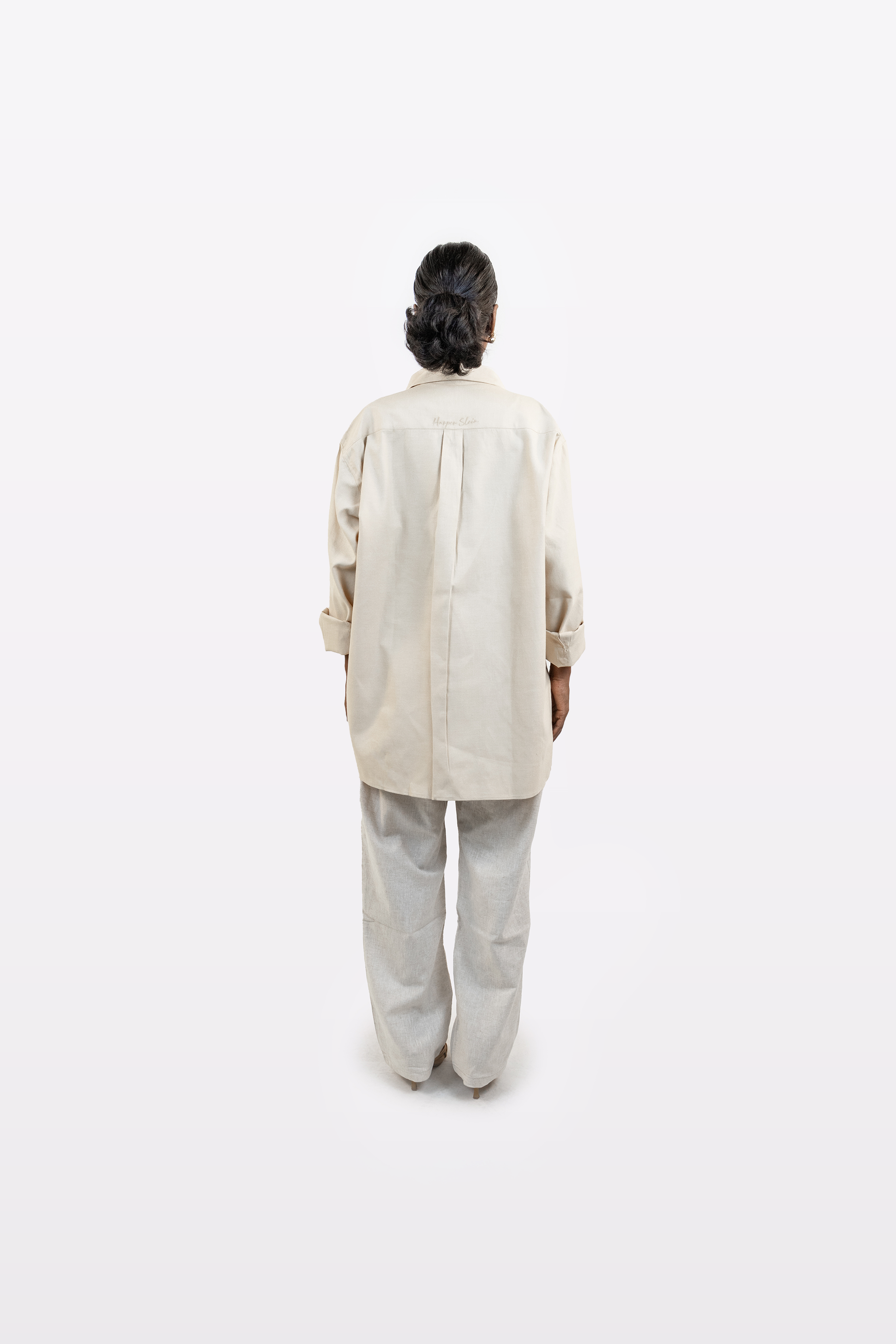 Full back profile of a model wearing the Harper Slein Off White Oxford Shirt with light trousers on a white background