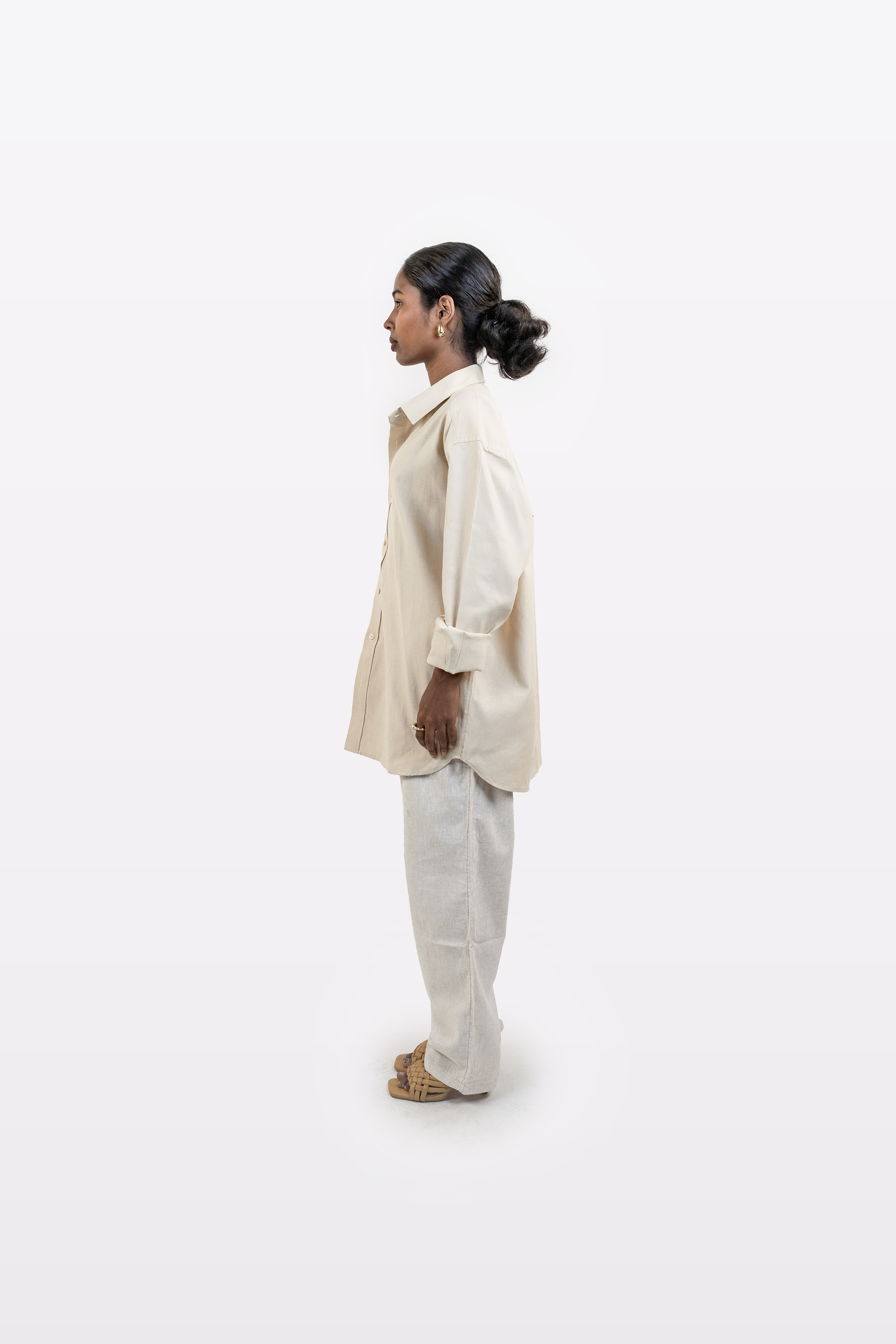 Right side profile of a model wearing the Harper Slein Off White Oxford Shirt with light trousers on a white background
