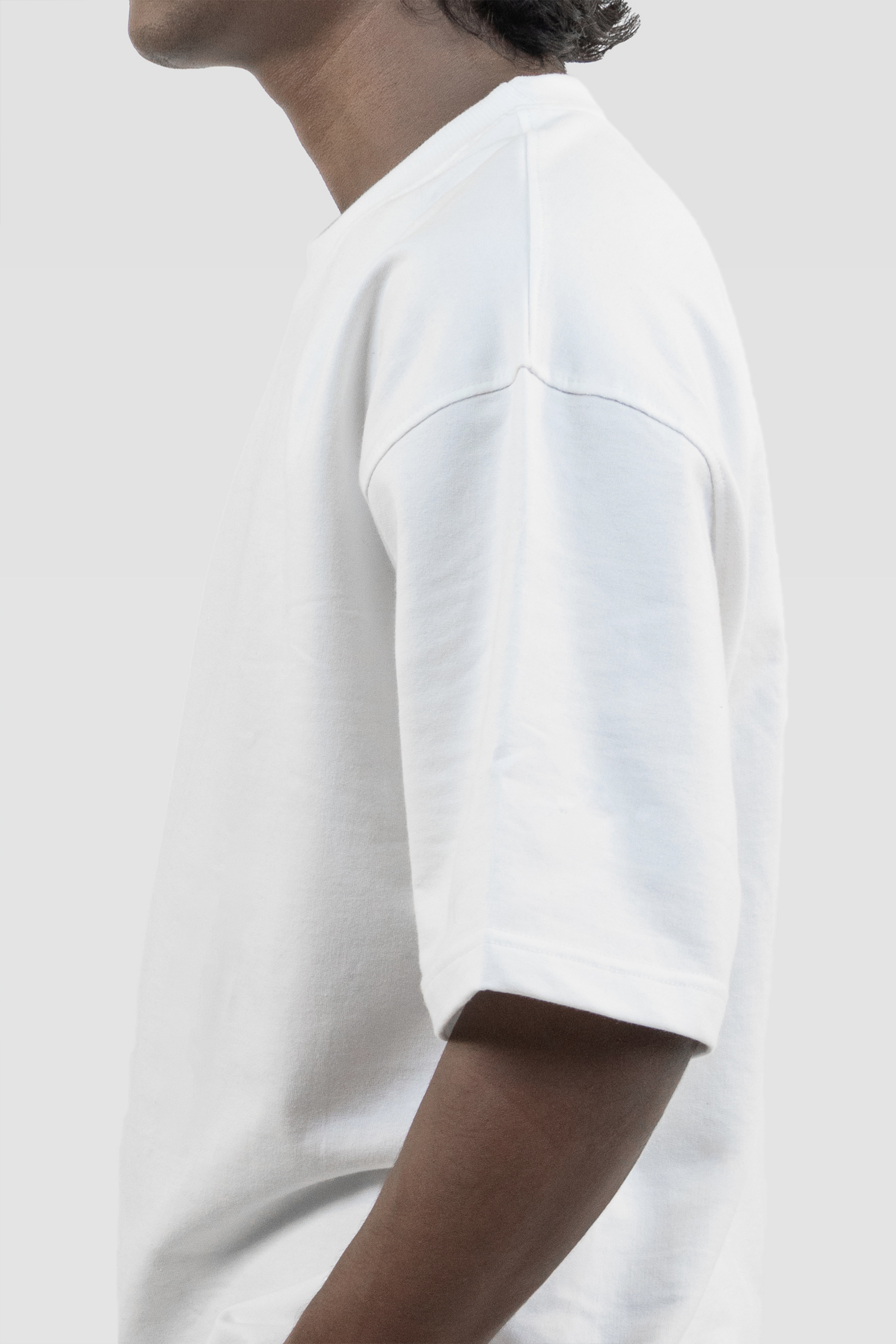 Side profile of a model wearing Harper Slein oversized t-shirt in Blank White against a light background