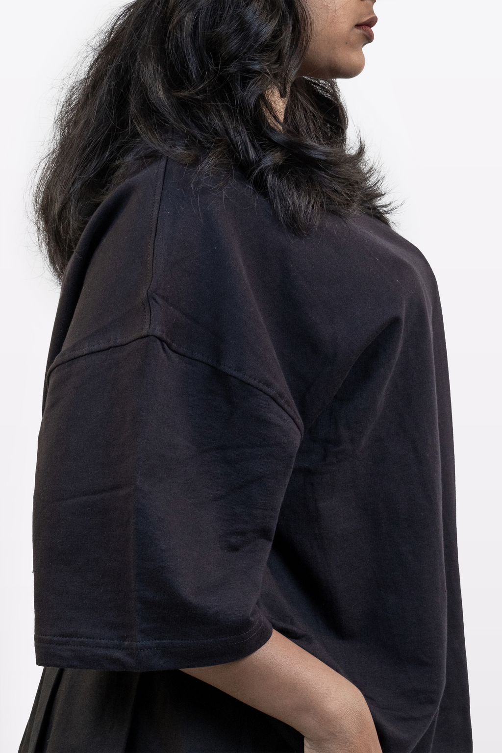 Close-up side view of female model wearing Harper Slein oversized t-shirt in Classic Black, highlighting shoulder seam, sleeve, and fabric texture against a white background