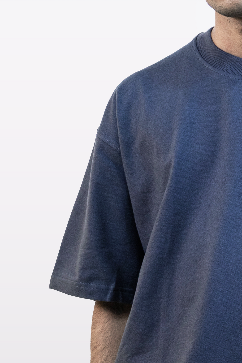 Upper body close-up of model wearing Harper Slein oversized t-shirt in Compass Blue, highlighting shoulder and chest area, on a white background