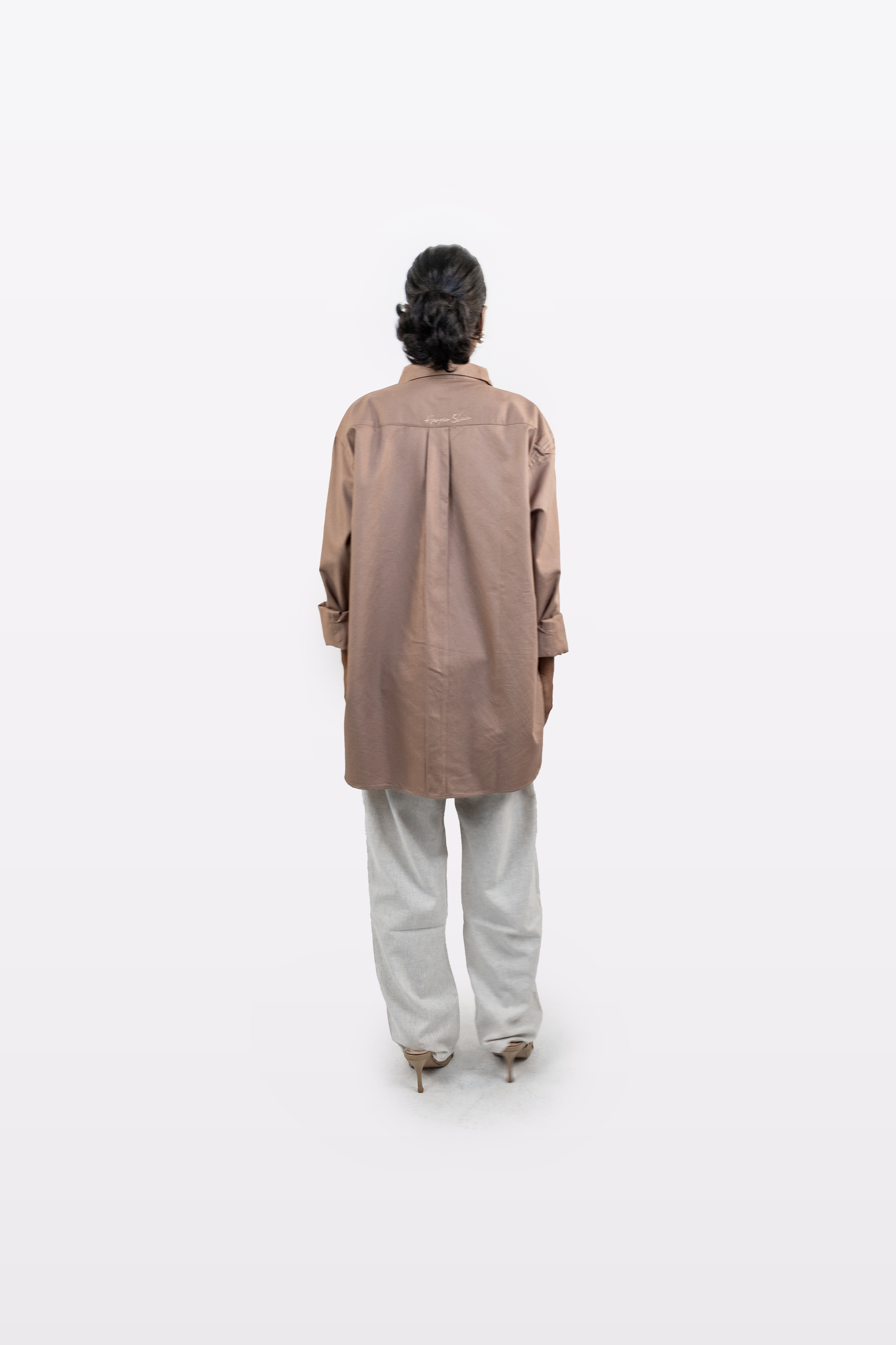Back view of a model wearing the Harper Slein Brown Oxford Shirt with light trousers on a white background.