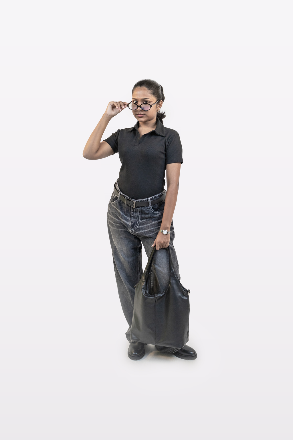 Model wearing Harper Slein ribbed black polo t-shirt styled with relaxed jeans, carrying a black tote bag, and posing with glasses, on a white background