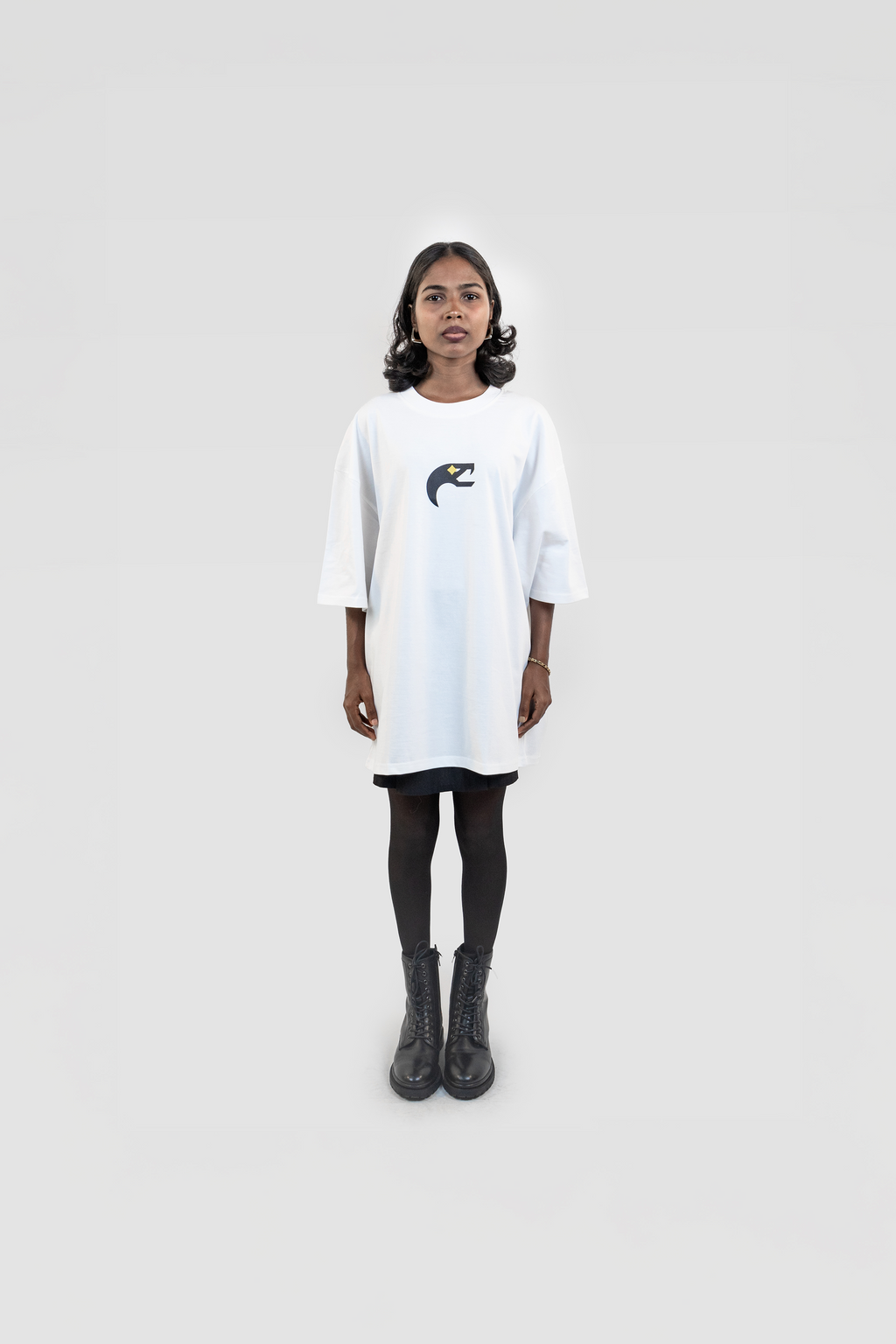 Front view of the Harper Slein Urban Crew Collection Snake Logo T-Shirt in white, featuring a black and yellow snake emblem on the chest, worn as an oversized fit with black tights and combat boots against a white background.