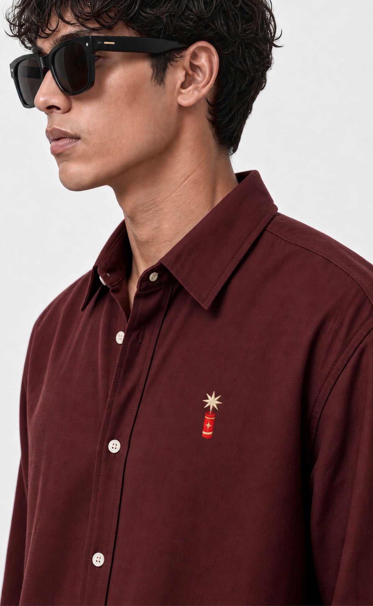 Close-up of the firecracker chest motif on the burgundy cotton shirt