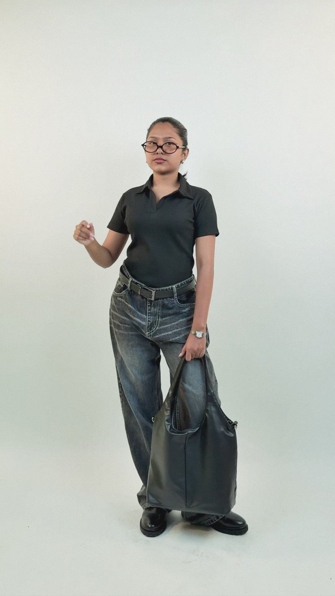 Harper Slein black polo shirt in a tailored yet relaxed fit, shown on female model styled first with washed black jeans and tote bag, then with pleated skirt and lace-up boots, featuring side and back views to highlight its versatile design.
